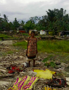 Lina Gawai ari genturung orang bansa asal Bumbu, PNG, benung begambar bediri atas tembawai rumah iya sebedau ti dirubuhka Rimbunan Hijau ti udah nya lalu muu sida pansut ari menua asal sida